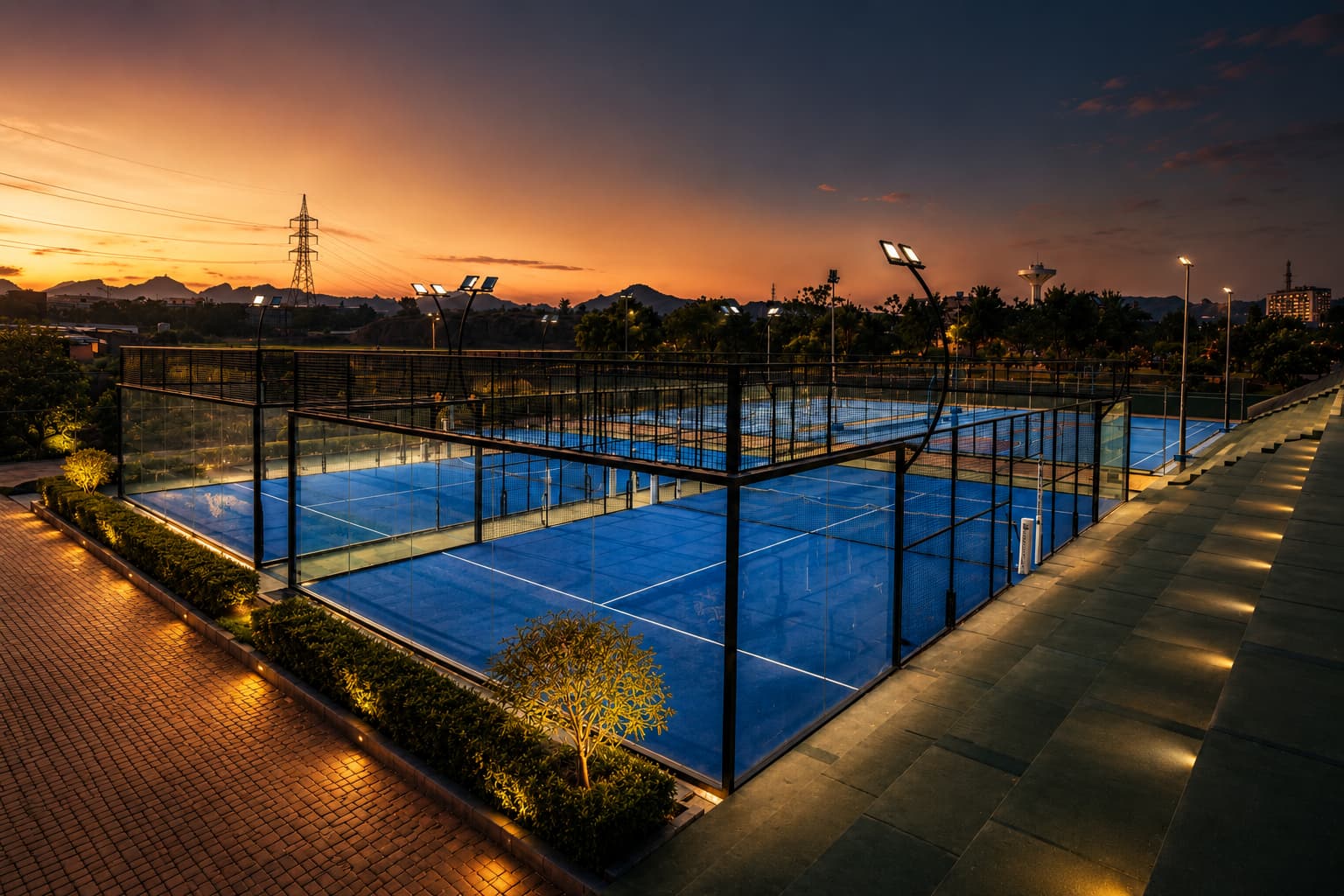 The floodlit padel courts at dusk at Grand Unicorn Club